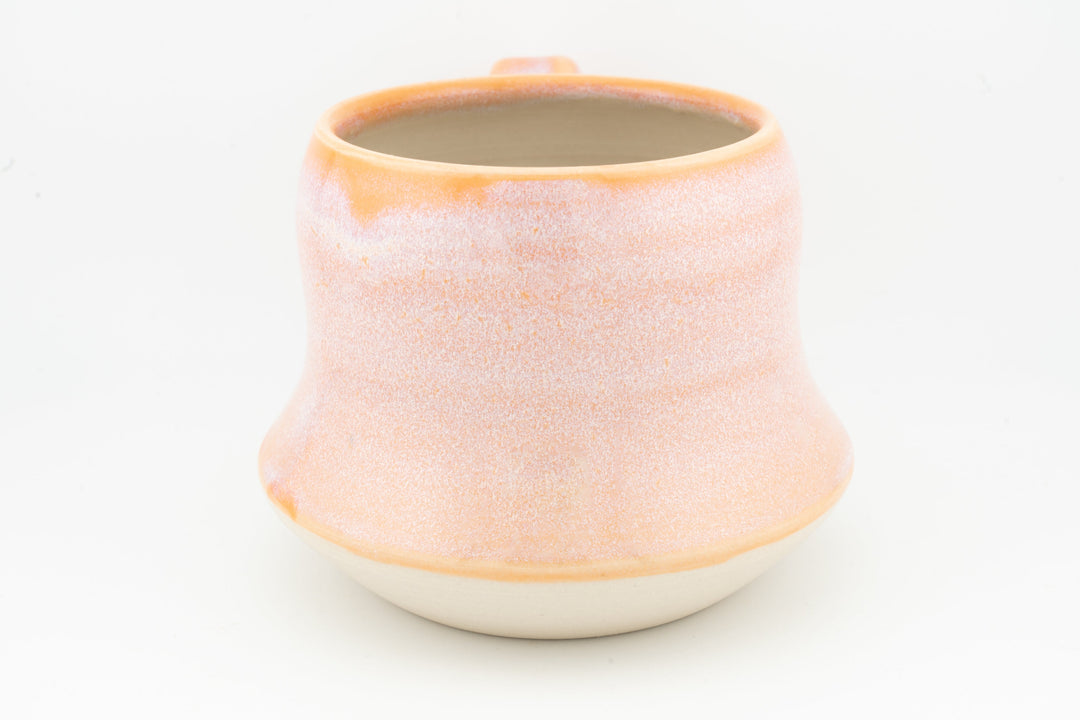 Peach-orange ceramic mug with textured speckled glaze, round lip and cream base