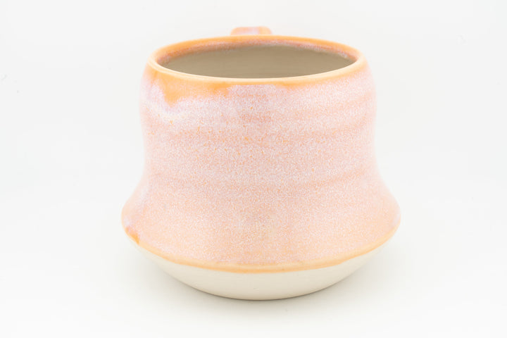 Peach-orange ceramic mug with textured speckled glaze, round lip and cream base