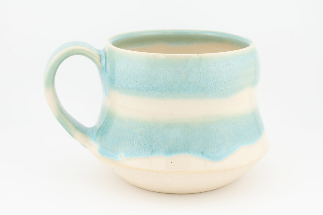Light blue ceramic mug with wide handle, horizontal stripe glaze and cream base