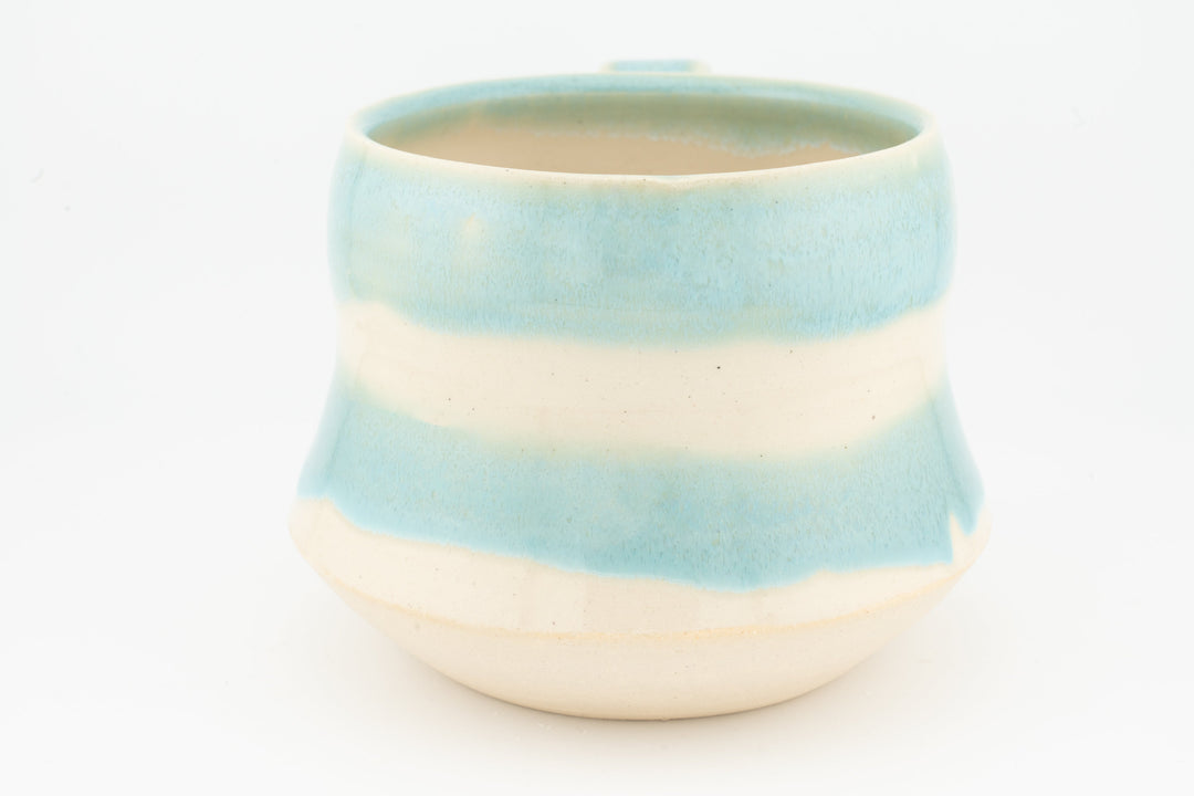 Light blue ceramic mug with layered stripe glaze, rounded lip and cream base