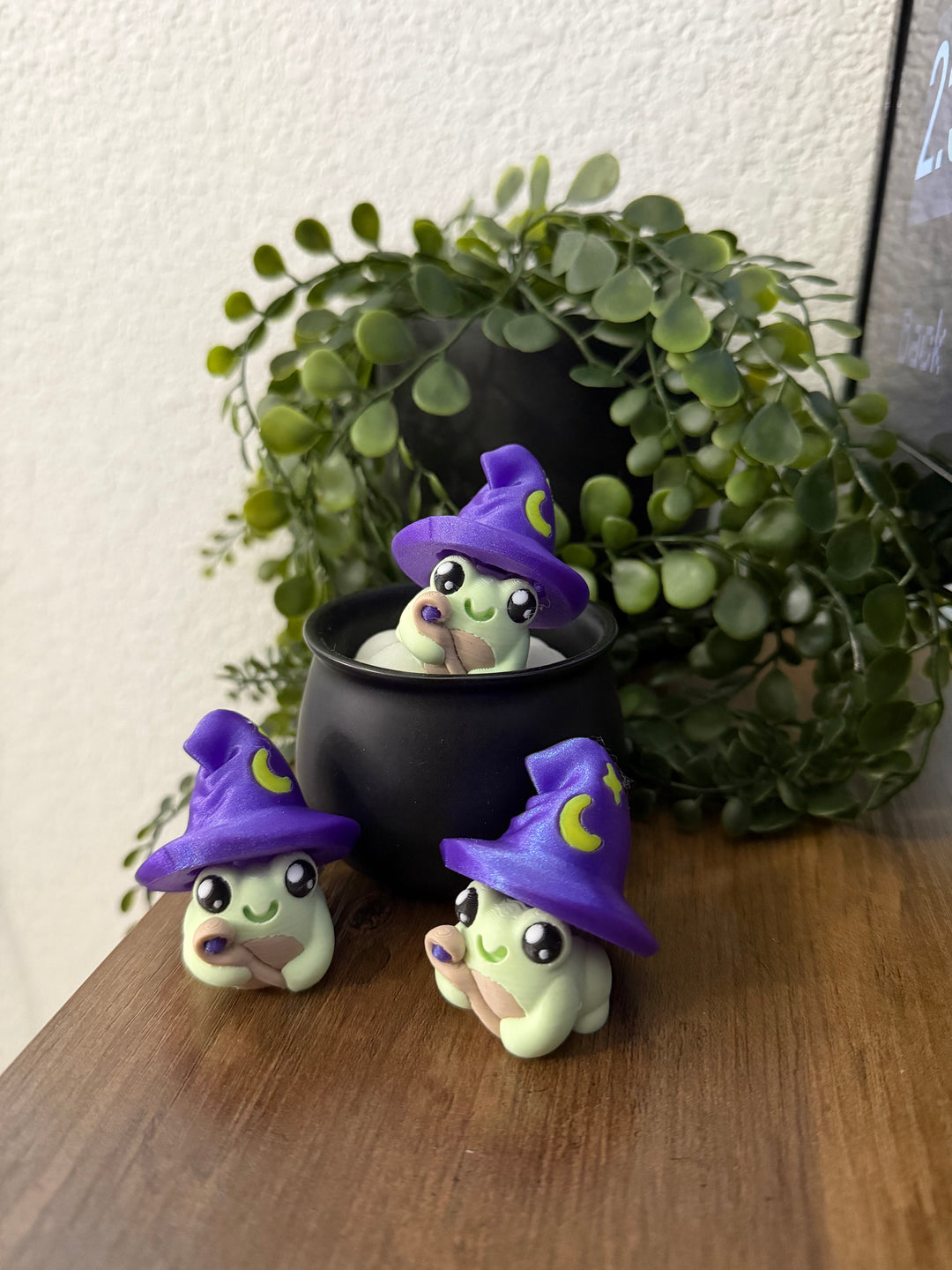 Frog toy with purple witch hat and moon emblem, crouching pose