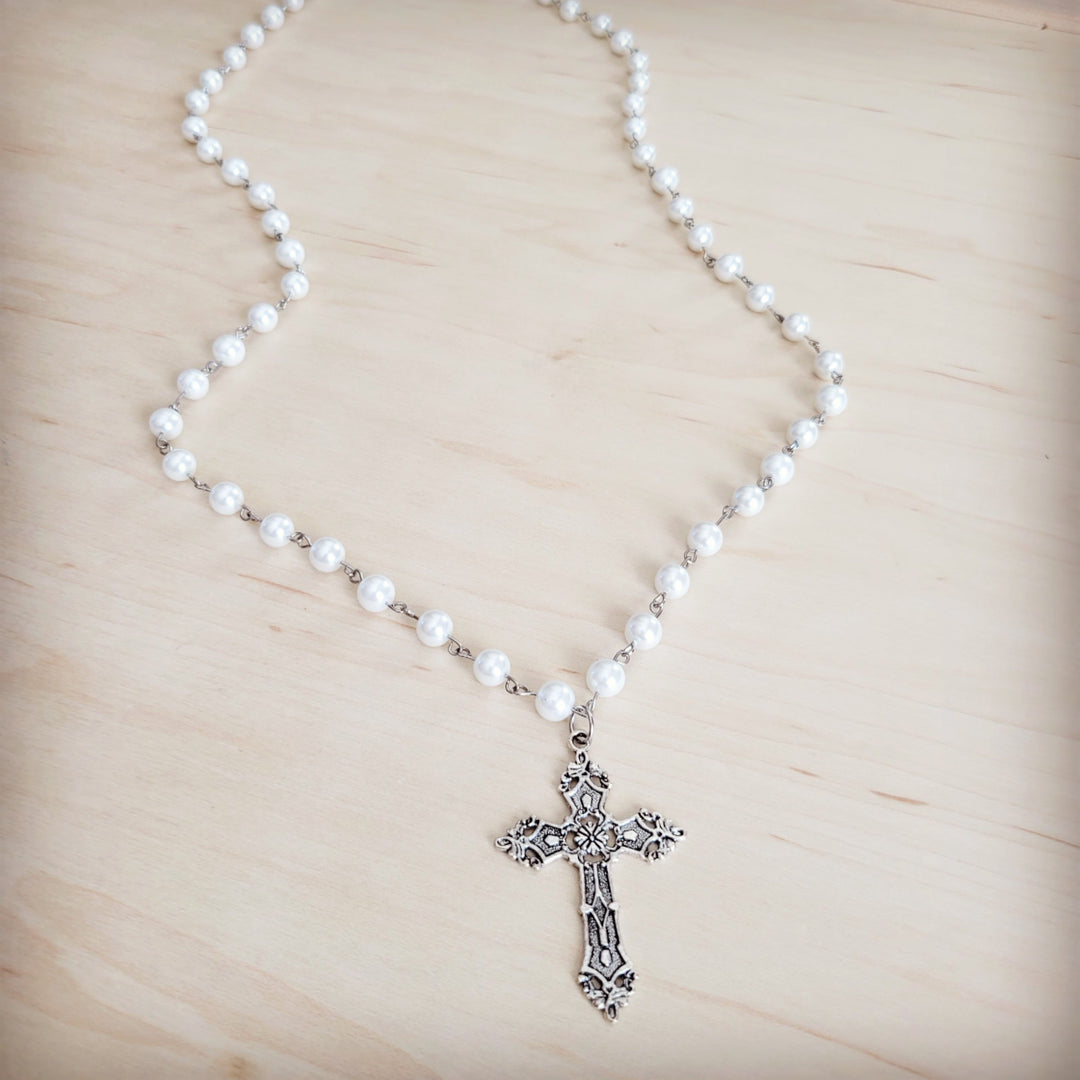 Long pearl beaded necklace with antique silver cross pendant, centered