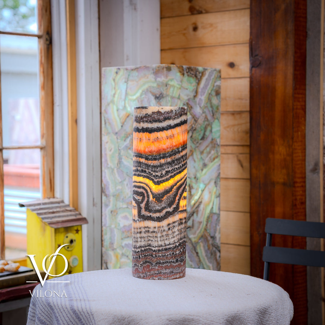 Cylindrical table lamp shade with multicolor wavy stripes and glowing orange center