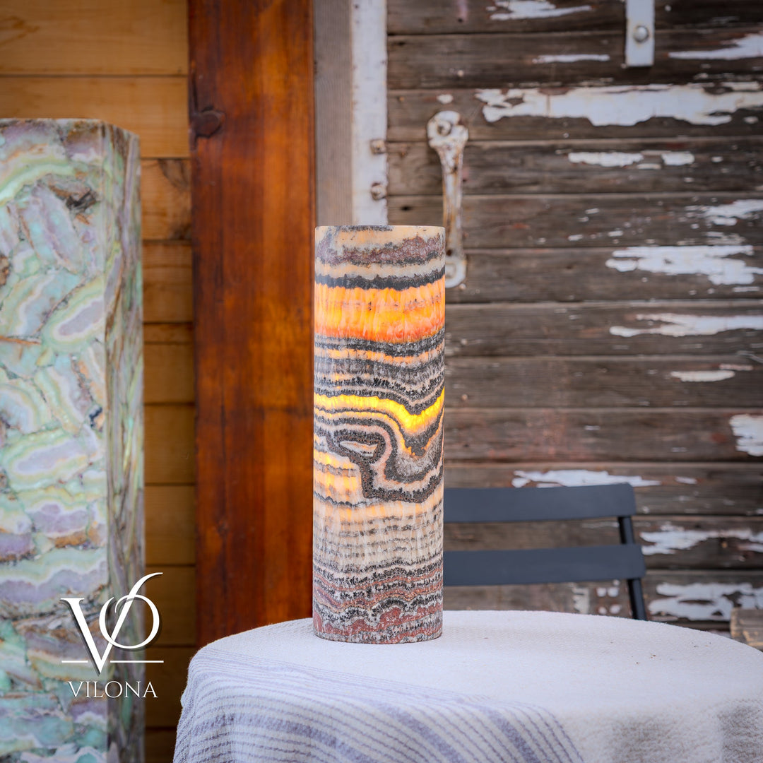 Tall cylindrical table lamp with multicolor striped shade and glowing orange center band