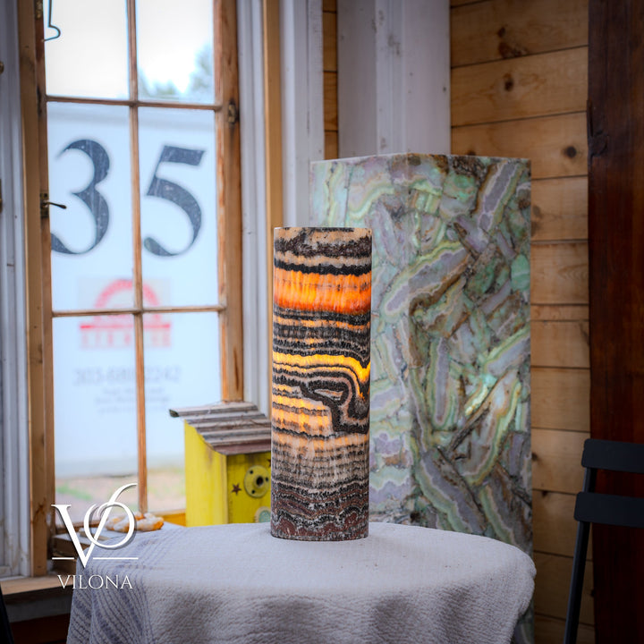 Patterned ceramic table lamp with cylindrical shade, multicolor swirled bands and warm glow