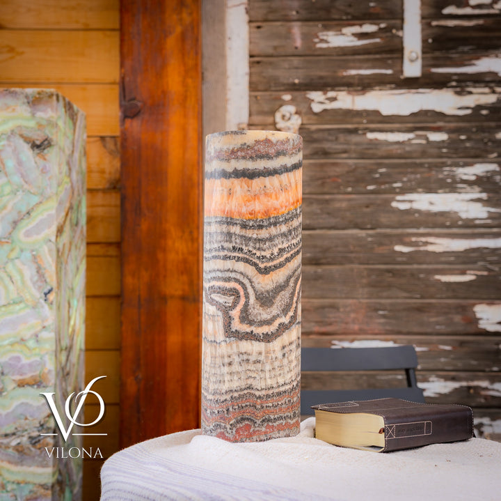 Tall table lamp with multicolor swirled bands on cylindrical shade, emitting warm light