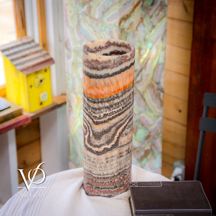 Narrow close-up of tall table lamp with cylindrical shade showing wavy orange and dark stripes