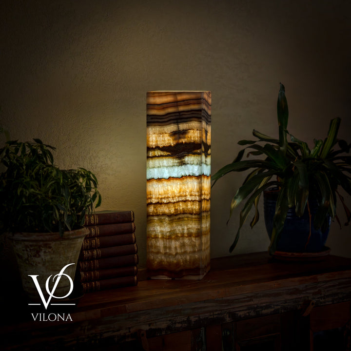 Square table lamp with lit striped onyx-style shade in amber, gold, cream, and dark bands