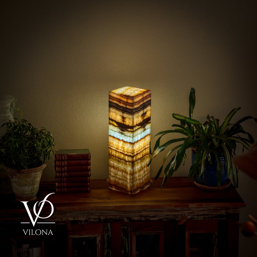 Square table lamp with glowing striped onyx-style shade in gold, cream, and blue-green
