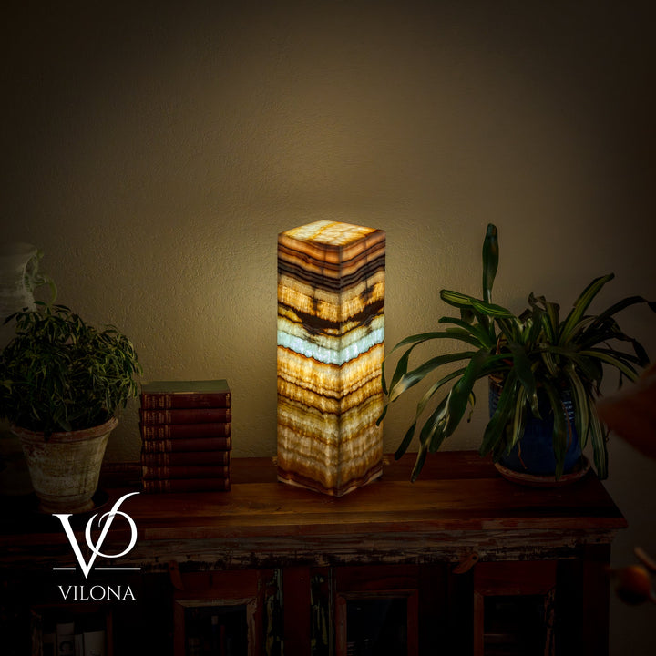 Square table lamp with glowing striped onyx-style shade in gold, cream, and blue-green