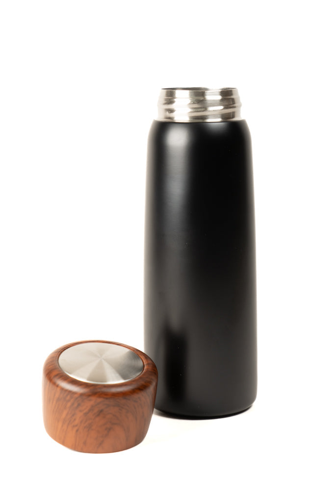 Black insulated tumbler with wooden lid detached, showing lid underside