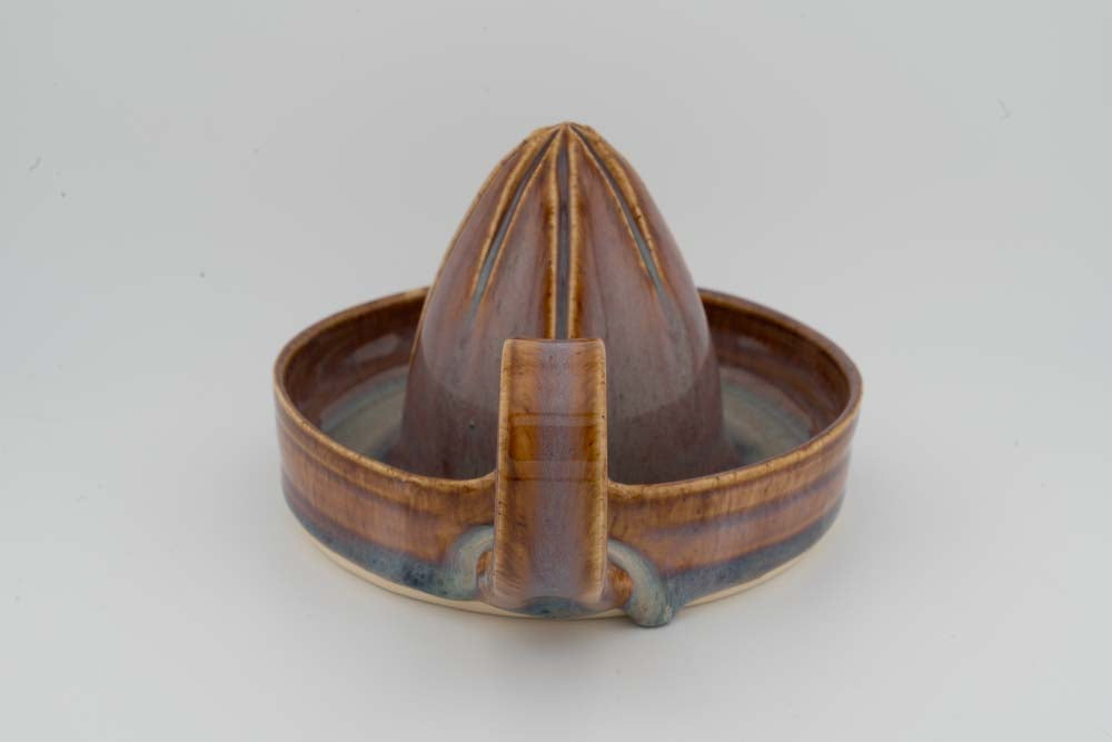 Brown ceramic citrus juicer cone reamer with drip tray spout detail and central base block.