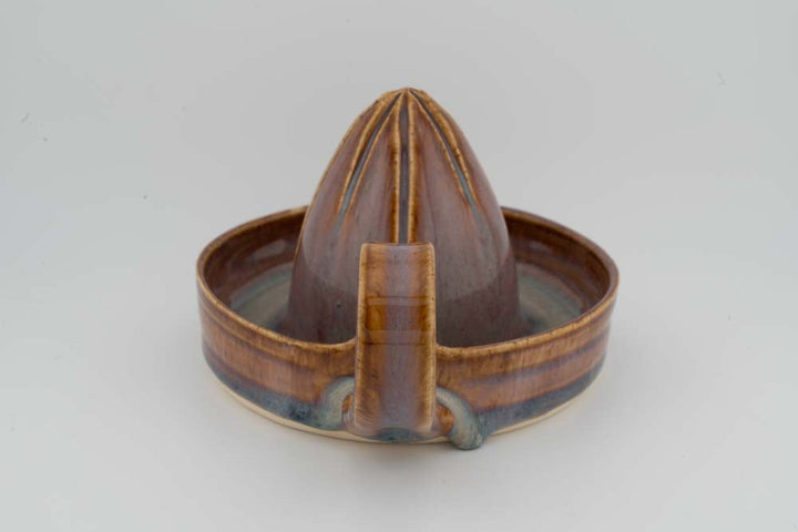 Brown ceramic citrus juicer cone reamer with drip tray spout detail and central base block.