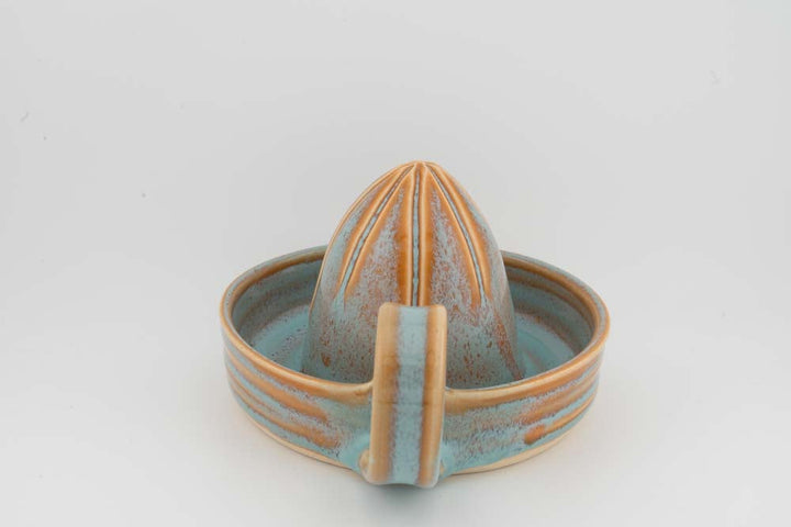 Ceramic citrus juicer with turquoise tray glaze and pale orange vertical cone detail.