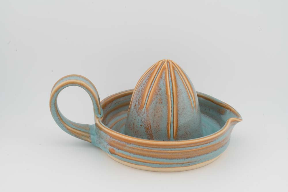 Ceramic citrus juicer with blue-green tray, upright cone, and curved side handle.