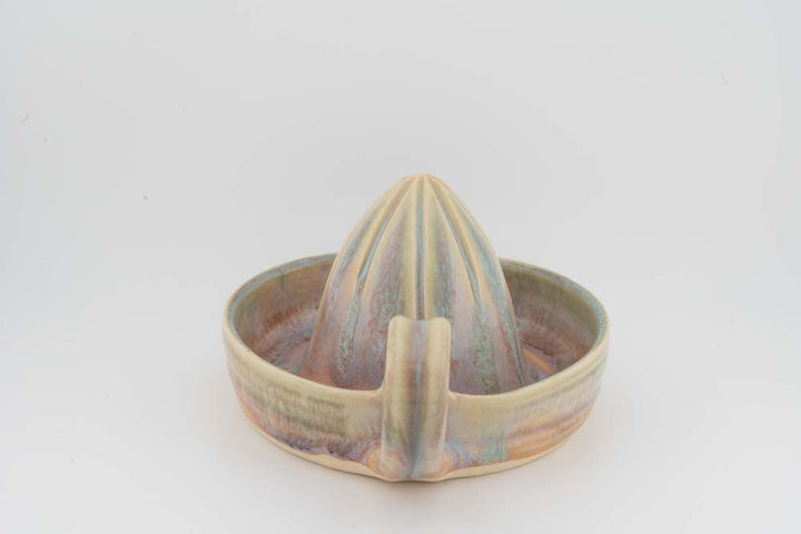 Ceramic citrus juicer with beige tray glaze, central cone, and curved pouring spout.