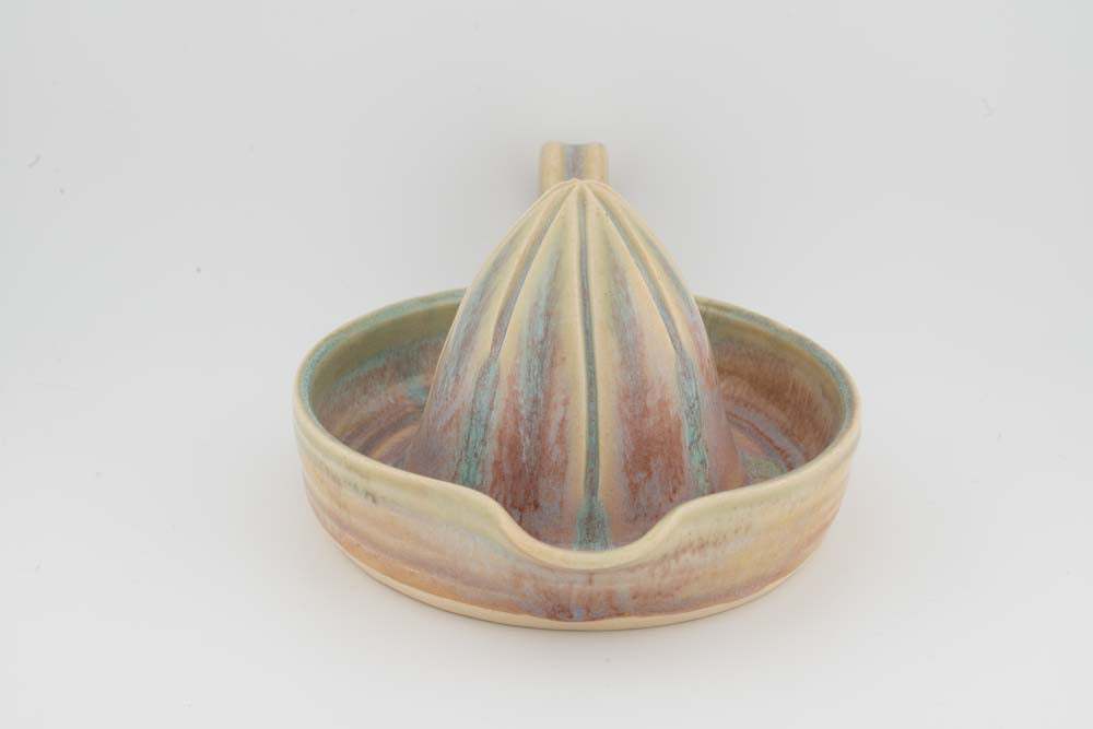 Ceramic citrus juicer with beige-and-green glazed tray and centered upright cone.