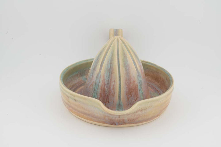 Ceramic citrus juicer with beige-and-green glazed tray and centered upright cone.