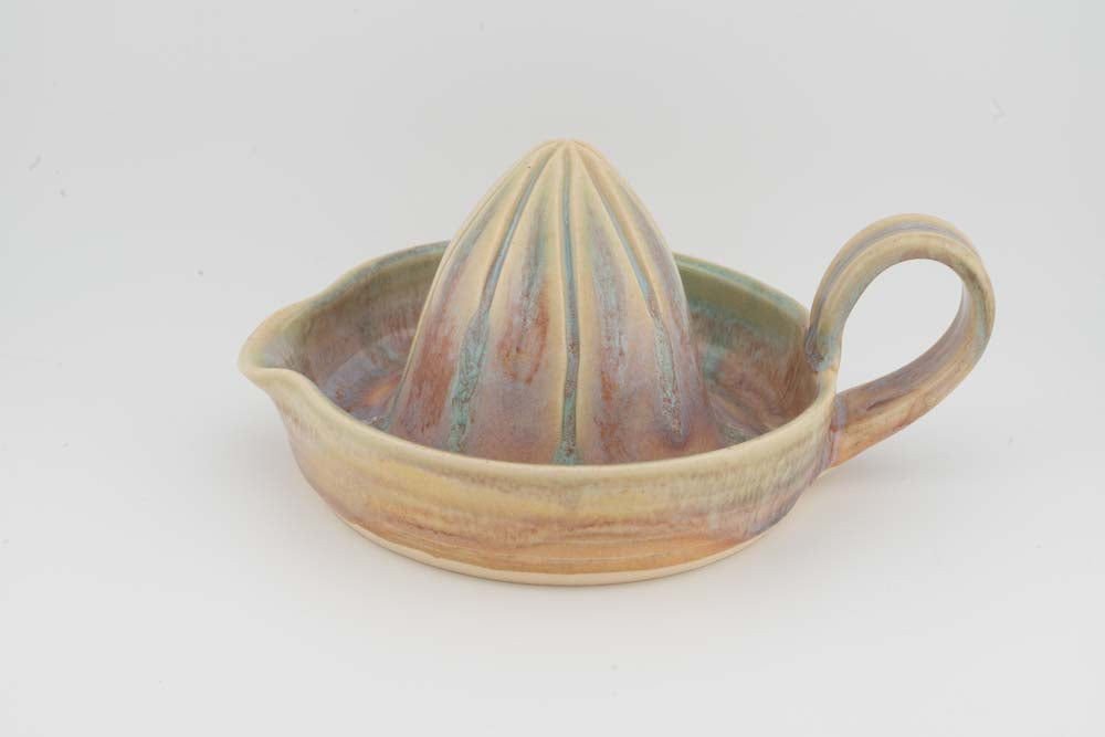 Ceramic citrus juicer with multicolor glaze, upright cone, and matching side handle.