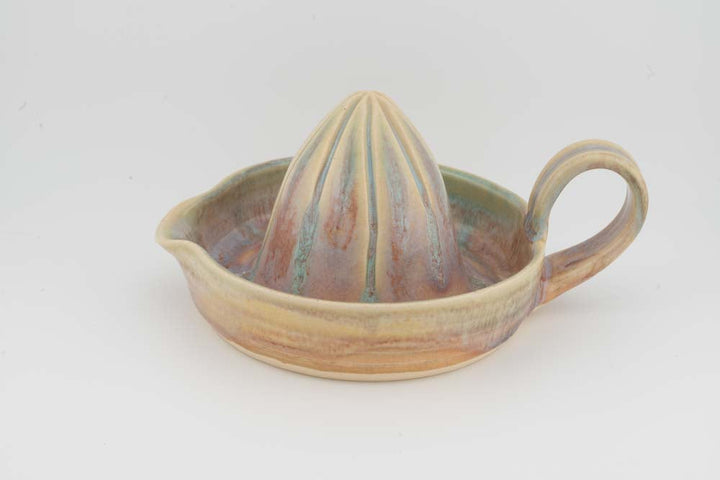 Ceramic citrus juicer with multicolor glaze, upright cone, and matching side handle.