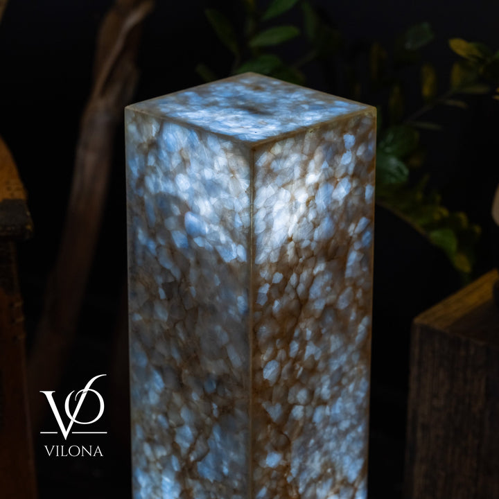 Close-up square small floor lamp with blue onyx-like texture and glowing interior.