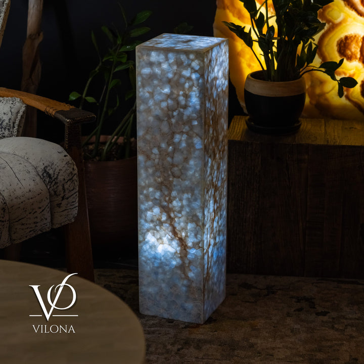 Square small floor lamp in a blue onyx-style finish with bright warm light inside.