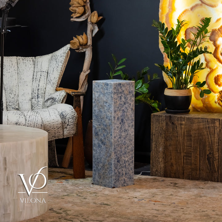 Small square blue stone floor lamp, glowing pillar standing between seating and decor