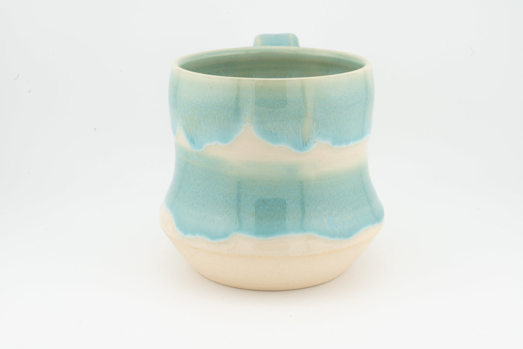 Light turquoise speckled tall ceramic mug with open rim and rounded base