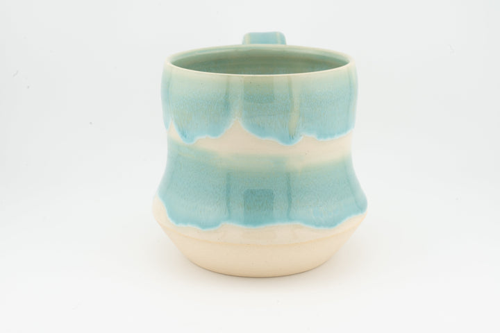 Light turquoise speckled tall ceramic mug with open rim and rounded base