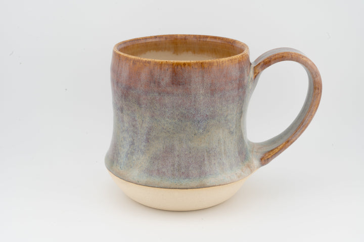 Tall ceramic mug with mottled brown and gray glaze, rounded handle, cream base