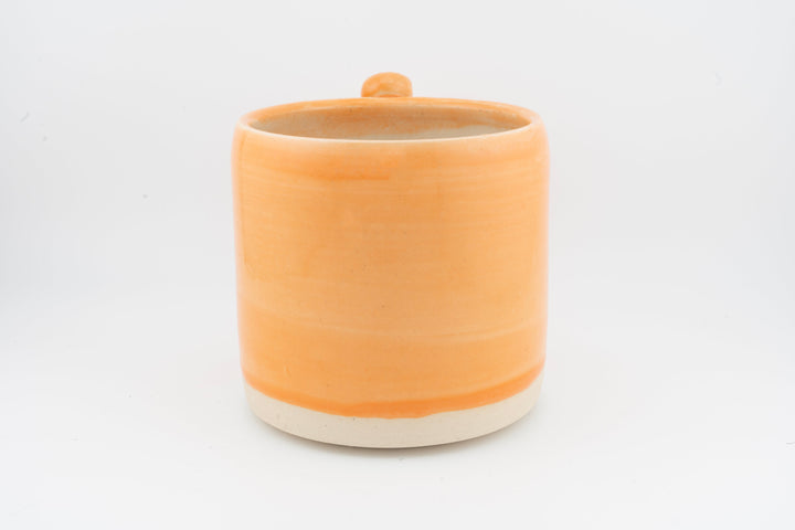 Ceramic mug with orange glaze and open top, creamy base