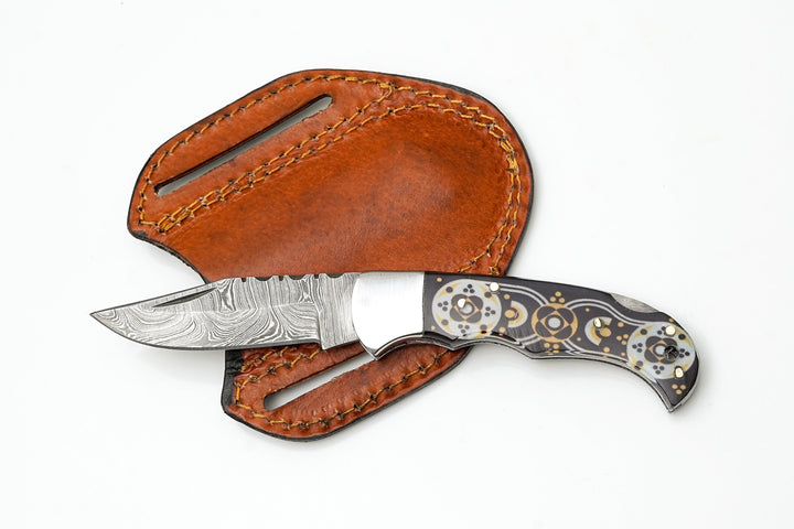 Folding knife with Damascus drop-point blade, black/gold mosaic handle and open leather carry pouch