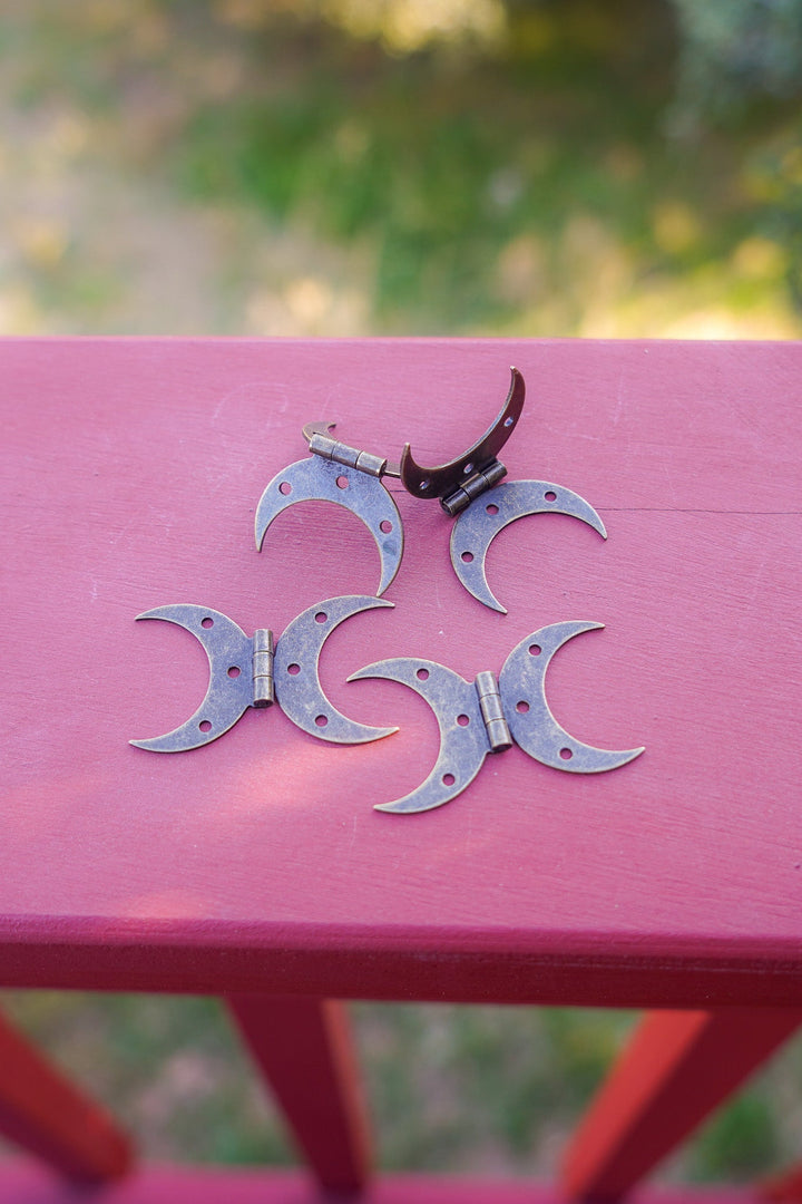 Bronze-finished crescent moon hinges shown on a wooden surface