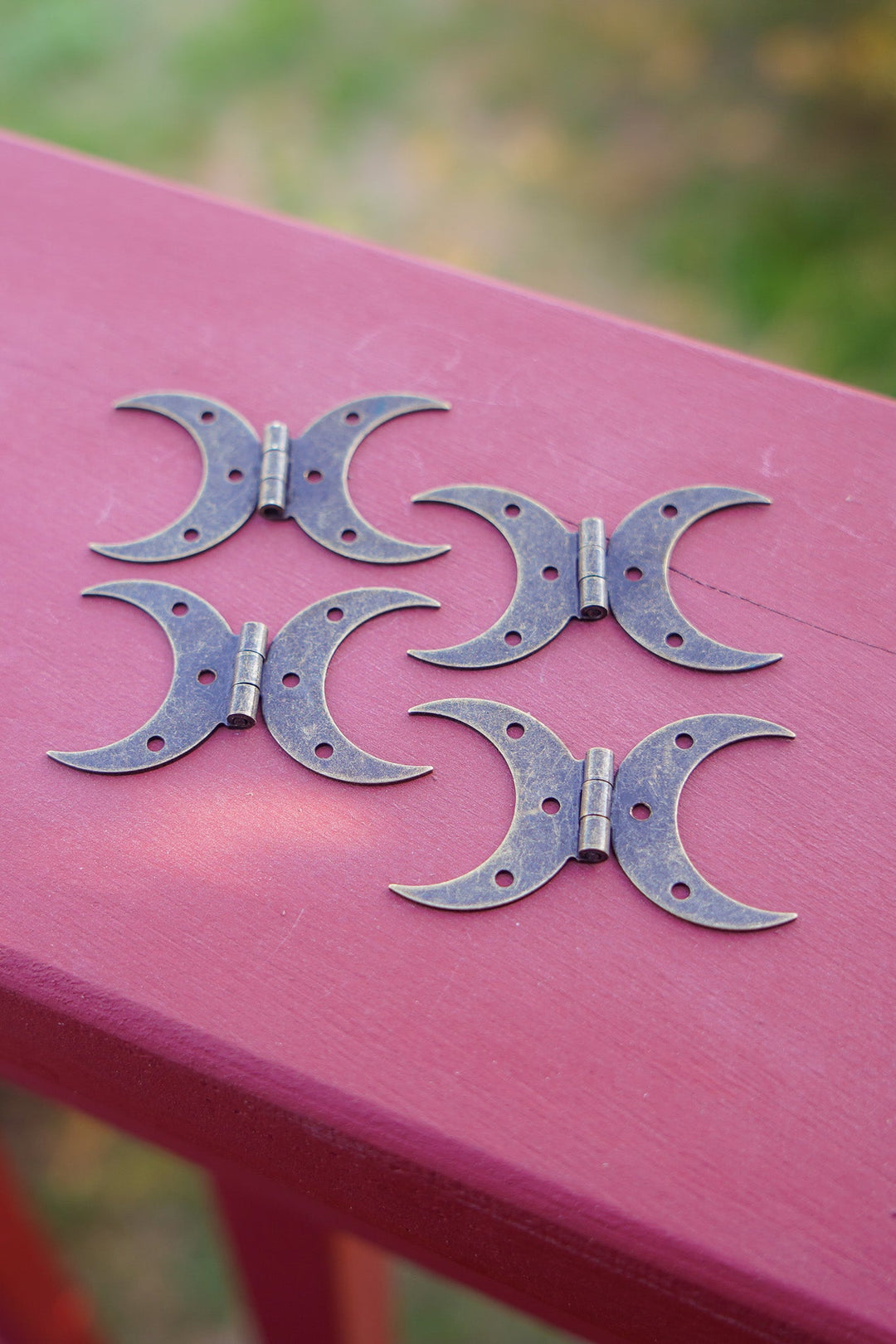Bronze-finished steel crescent moon hinges with matching screws on wood