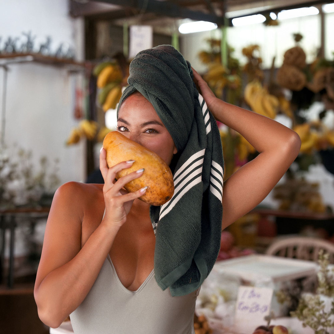 Dark green Australian cotton towel with white striped trim wrapped on head