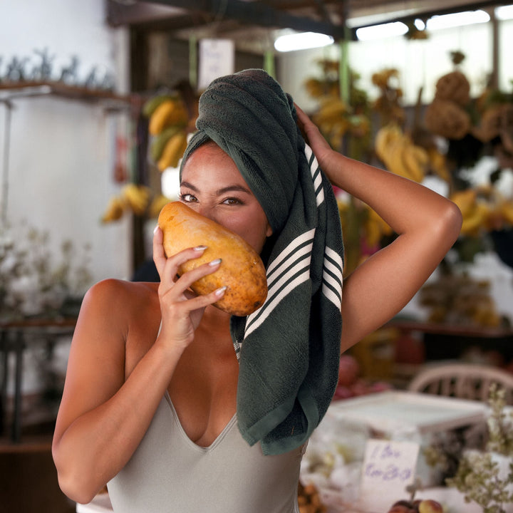 Dark green Australian cotton towel with white striped trim wrapped on head