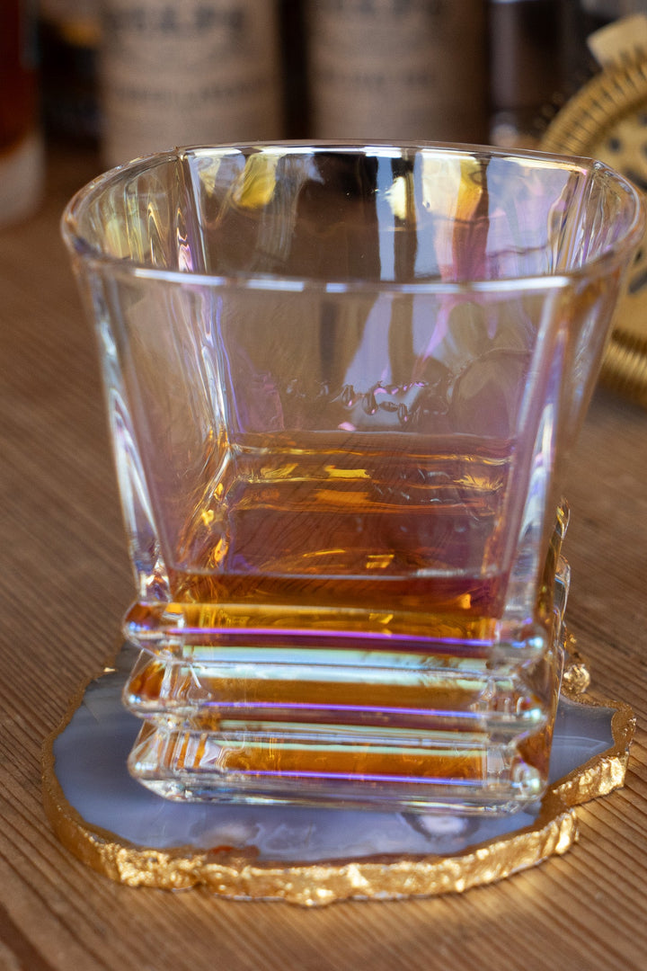 Iridescent lowball whiskey glass on gold base, shown at angled front view