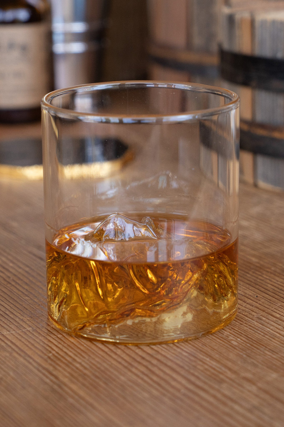 Whiskey tumbler with ice cubes and mountain range etched design on the glass