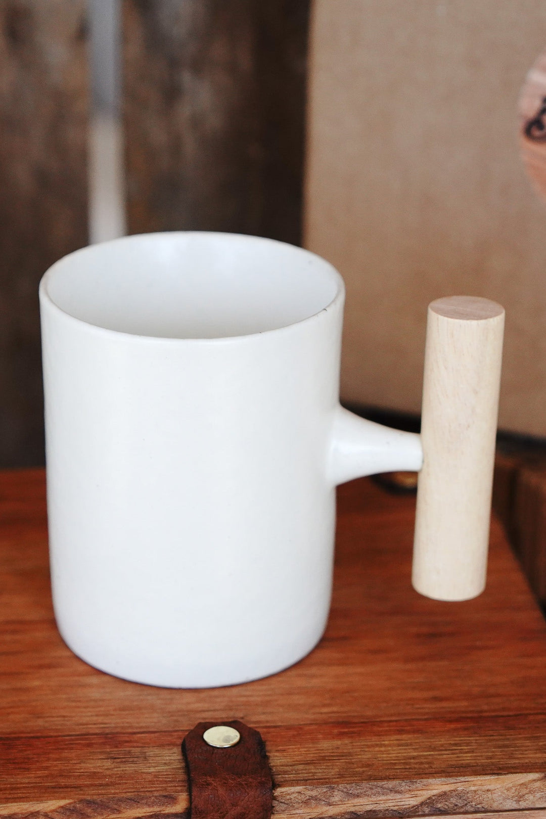 White glazed ceramic mug with wooden handle on tabletop