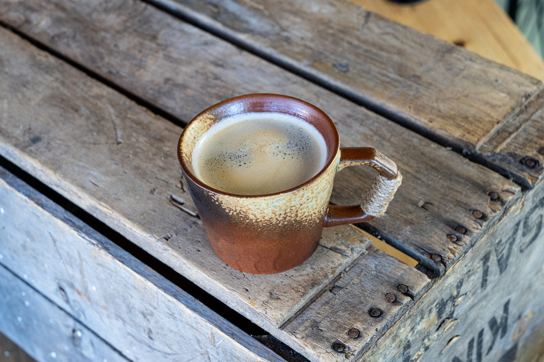 Small speckled ceramic coffee mug with wrapped handle and filled interior