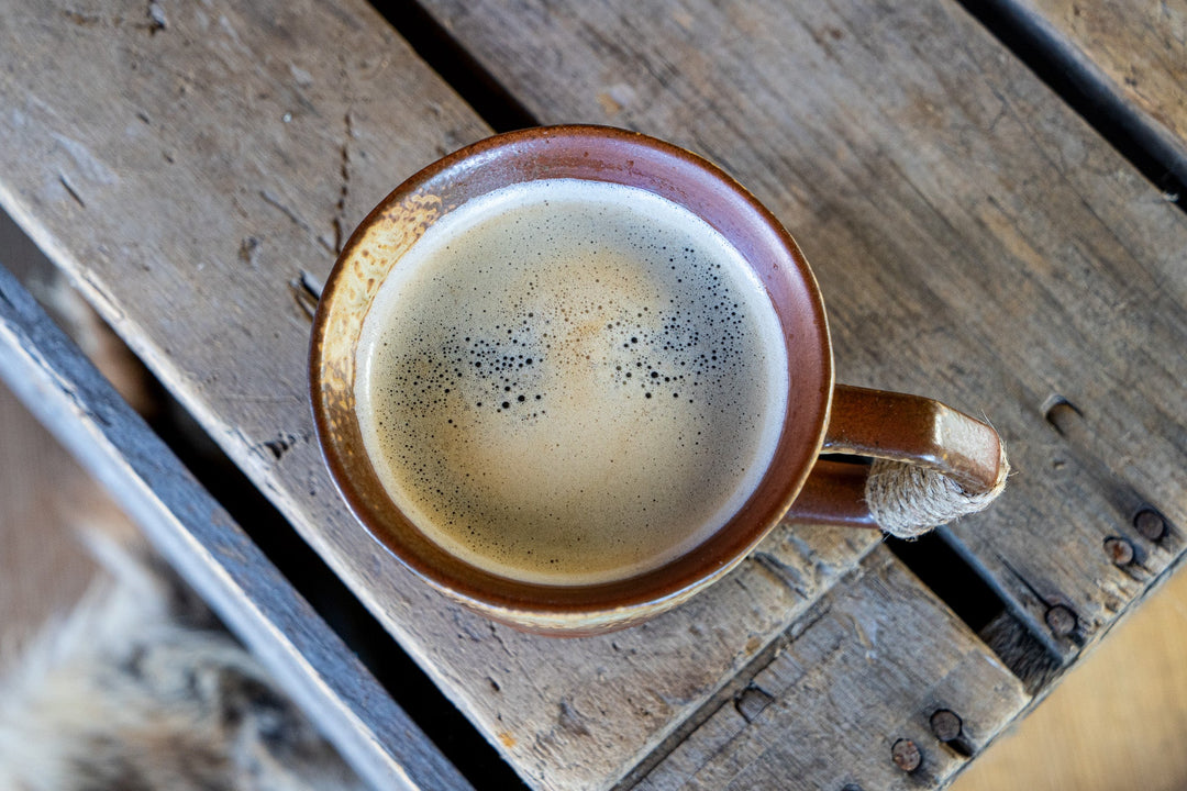 Round ceramic coffee mug with speckled glaze, filled cup, wrapped side handle