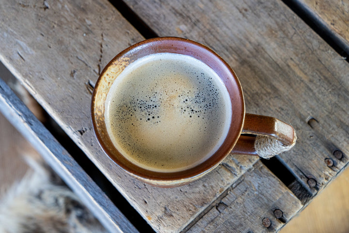 Round ceramic coffee mug with speckled glaze, filled cup, wrapped side handle