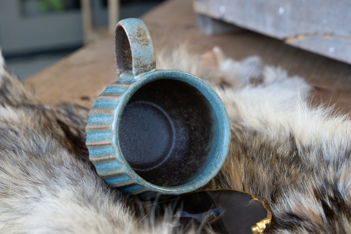 Handmade turquoise striped ceramic mug, open top and handle viewed from above
