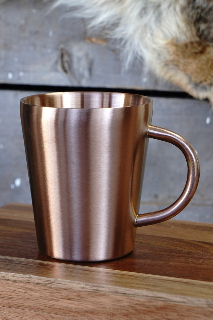 Copper double wall stainless steel mug with copper handle on wood surface