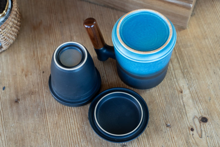 Blue ceramic mug set with dark lid and base, plus small cup pieces