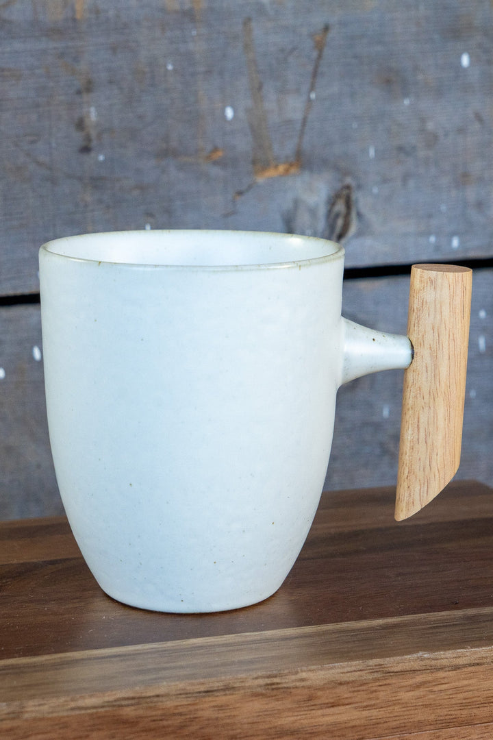 White speckled ceramic mug with curved wooden handle and short spout