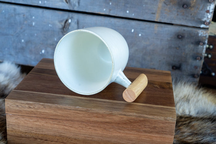 White ceramic mug with wooden handle, top-down view of open cup