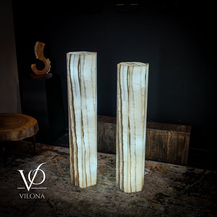 Pair of white onyx floor lamps with softly glowing bases and narrow vertical striations