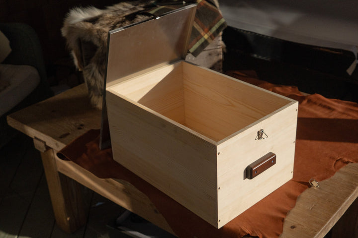 Light wood storage box open, showing interior and dark handle latch