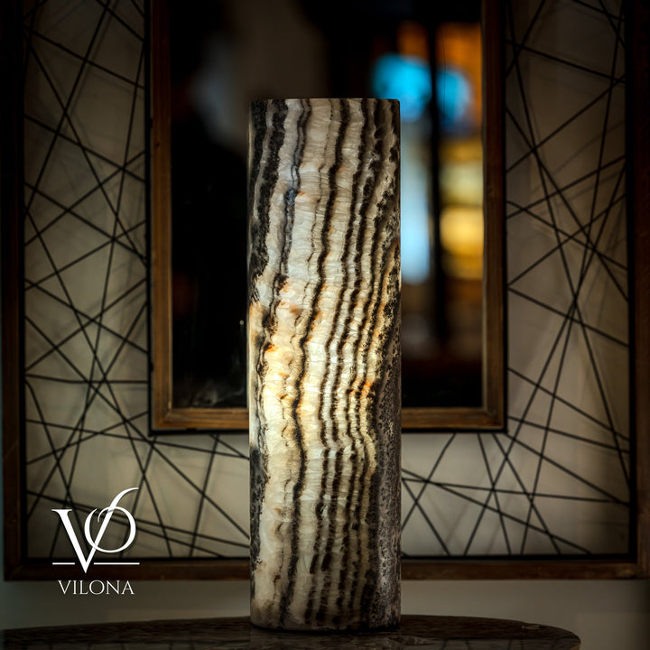 Onyx table lamp base with vertical cream striations and dark bands; cord visible.
